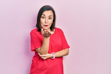 Middle age hispanic woman wearing casual clothes looking at the camera blowing a kiss with hand on air being lovely and sexy. love expression.