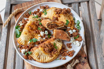 Empanadas with spicy minced meat and feta cheese filling on a plate