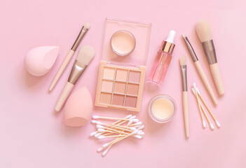 Natural beige eye shadow and decorative cosmetics on light pink, top view