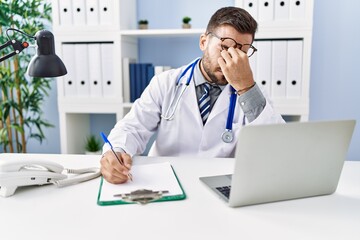 Young hispanic man wearing doctor uniform stressed working at clinic