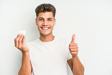 Young caucasian man hand sling isolated on white background smiling and raising thumb up