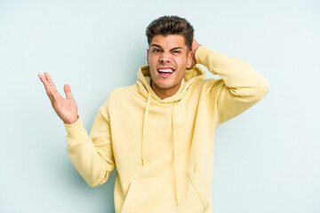 Young caucasian man isolated on blue background screaming with rage.