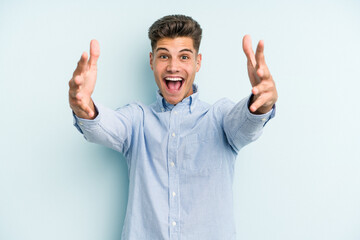Young caucasian man isolated on blue background celebrating a victory or success, he is surprised and shocked.