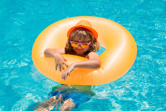 Child in swimming pool on inflatable ring. Kid swim with orange float. Water toy, healthy outdoor sport activity for children. Kids beach fun.