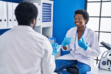 African american man and woman scientists working together speaking at laboratory
