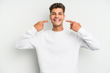 Young caucasian man isolated on white background smiles, pointing fingers at mouth.
