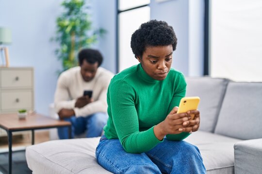 African american man and woman couple using smartphone with problems at home
