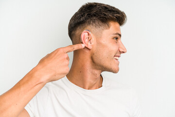 Young caucasian man wearing a hearing aid isolated on white background