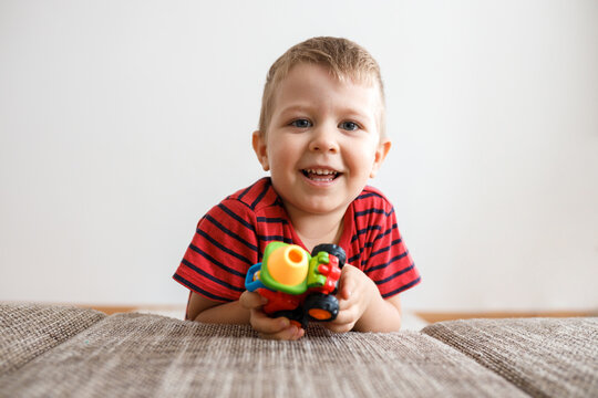 cute little boy of three with a toy in his hands at home by the couch.