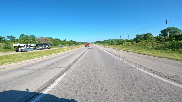 POV while driving on The Avenue of the Saints through rural Iowa; approaching a construction signs; the highway connects St Paul to St Louis; driving past fields and agricultural landscapes