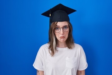 Blonde caucasian woman wearing graduation cap depressed and worry for distress, crying angry and afraid. sad expression.