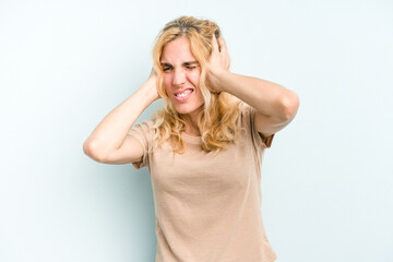 Fototapeta premium Young caucasian woman isolated on blue background covering ears with hands.