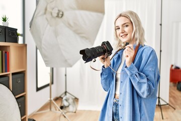 Beautiful blonde woman working as professional photographer at photography studio. Standing holding sdxc storage memory card