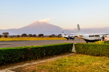 Small propeller airplanes at the airport at sunset, mount Meru at background. Arusha, Tanzania - obrazy, fototapety, plakaty
