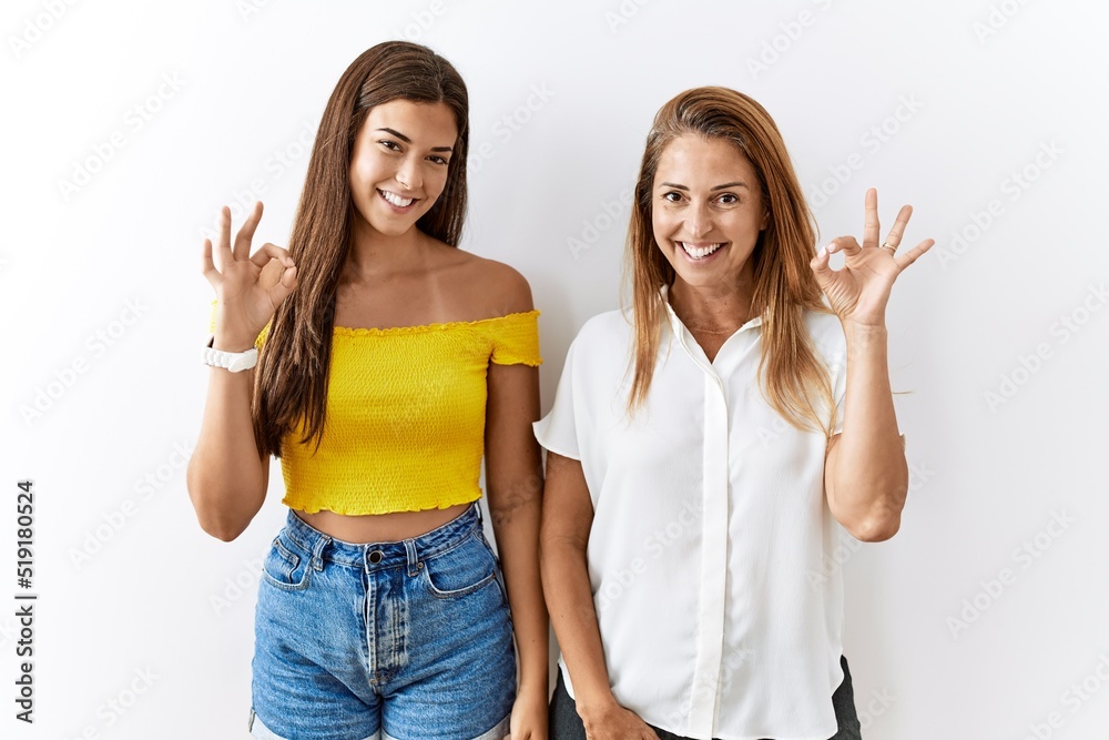 Wall mural Mother and daughter together standing together over isolated background smiling positive doing ok sign with hand and fingers. successful expression.