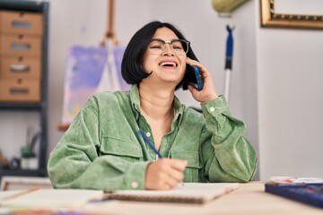 Young chinese woman smiling confident talking on the smartphone at art studio