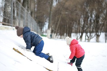 Children play outside in the winter. Snow games on street.