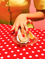 Colorful image of delicious oyster and female hands isolated on red tablecloth