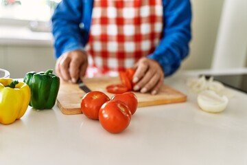 Senior man cutting tomato at kitchen