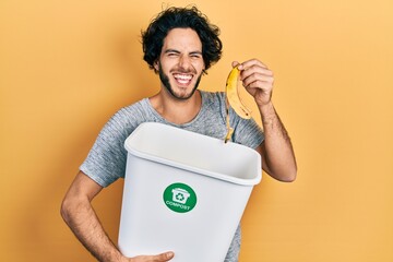Handsome hispanic man recycling banana peel composting organic fertilizer smiling and laughing hard...