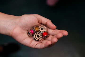 Latin American seamstress holds in her hand the thread spools of the sewing machine.