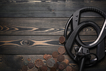 Recreational metal detector and ancient coins on the wooden table background with copy space. Treasure hunting concept background.