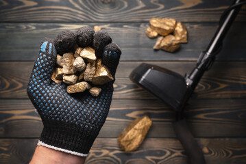 Hand with the golden ore and metal detector close up. Treasure hunting concept.
