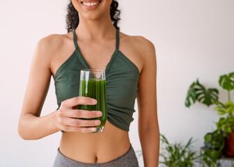 A beautiful multi-ethnic woman smiles with green juice - spinach, kale, vitamans
