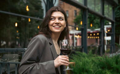 A young woman with a glass of wine outside near a restaurant.