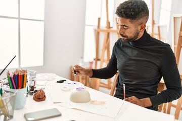 Young african american artist man concentrated painting pottery at art studio.