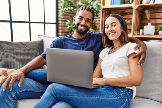 Man and woman couple using laptop hugging each other at home