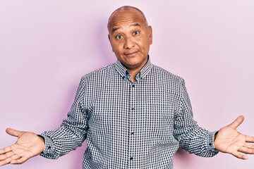 Middle age latin man wearing casual clothes clueless and confused expression with arms and hands...