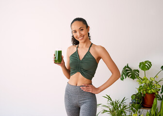 A beautiful multi-ethnic woman smiles with green juice - spinach, kale, vitamans