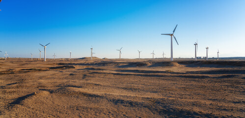 Wind power plants in desert at sunset