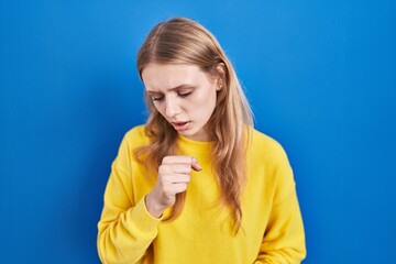 Young caucasian woman standing over blue background feeling unwell and coughing as symptom for cold or bronchitis. health care concept.
