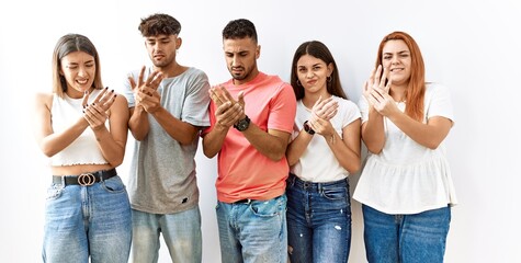 Group of young friends standing together over isolated background suffering pain on hands and fingers, arthritis inflammation