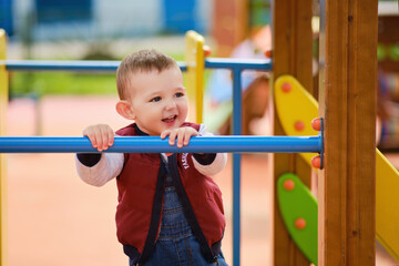 Happy toddler baby boy on the playground, smiling child aged one year