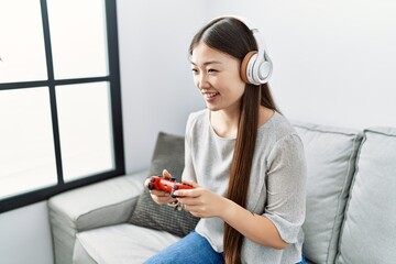 Young asian woman playing video games at the living room