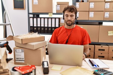 Young hispanic call center agent man working at warehouse relaxed with serious expression on face. simple and natural looking at the camera.