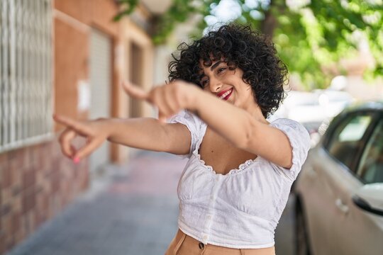 Young middle east woman smiling confident pointing with fingers at street