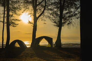 silhouette camping tent on beach with sunrise and sea background