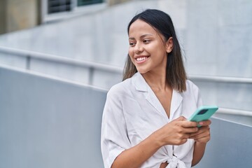 Obraz na płótnie Canvas Young hispanic woman smiling confident using smartphone at street