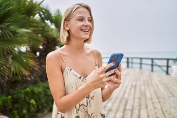 Young beautiful woman using smartphone by the sea