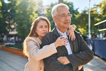Fototapeta premium Middle age man and woman couple hugging each other standing with relaxed expression at park