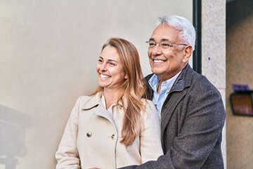 Middle age man and woman couple hugging each other standing at street