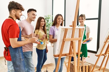 Group of people smiling happy drawing on canvas standing at art studio.