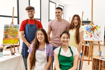 Group of five hispanic artists at art studio winking looking at the camera with sexy expression, cheerful and happy face.