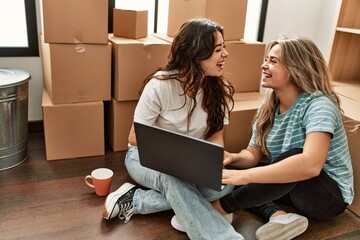 Young beautiul couple drinking coffee and using laptop at new home.