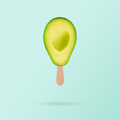 Fresh green avocado with ice cream stick on pastel blue background. Diet healthy concept. Creative summer concept..