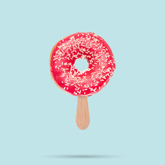 Pink donut Donut with sprinkles and ice cream stick on pastel blue background. Sweets concept. Creative summer concept..